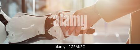 Beschnittene Ansicht einer Geschäftsfrau, die mit Roboter und Banner die Hand schüttelt Stockfoto