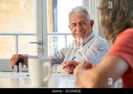 Lächelnder Senior mit Demenz, der zu Hause oder in einem Altersheim Gedächtnistraining macht Stockfoto