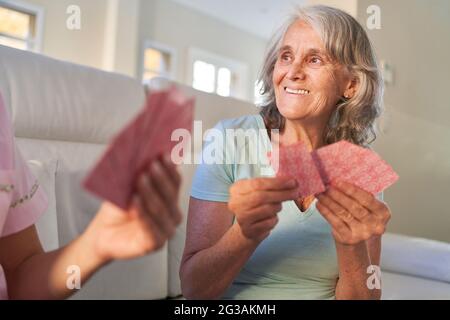 Ältere Frau spielt Karten mit Freunden in der Spielnacht zu Hause oder im Altersheim Stockfoto