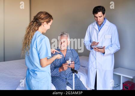 Medizinisches Team und leitender Patient während der Behandlung im Krankenhaus oder in einem Pflegeheim Stockfoto
