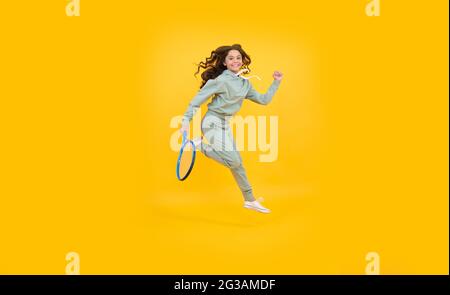 Energisches Kind mit Tennisschläger. Jugendliches Mädchen laufen zum Training. Gewidmet Fitness Stockfoto