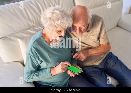 Rentnerehepaar schreibt gemeinsam eine SMS auf ihr Smartphone oder nutzt eine App Stockfoto