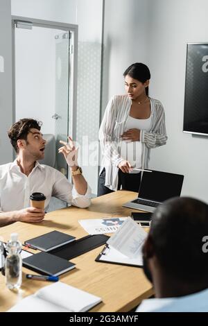 Ein Geschäftsmann, der während des Treffens mit einer afroamerikanischen Frau spricht und auf den Laptop zeigt Stockfoto