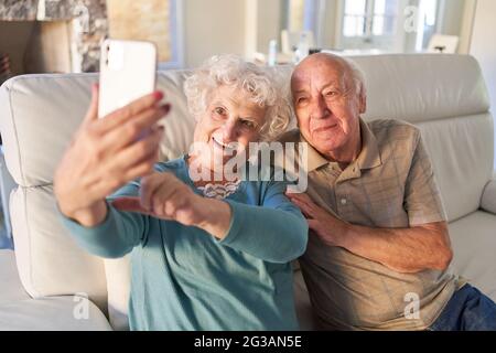 Glückliches Seniorenpaar, das ein Selfie mit dem Smartphone in der Seniorenresidenz macht Stockfoto