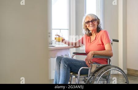 Zufriedener Senioren im Rollstuhl nach einem Schlaganfall zu Hause oder in einem Pflegeheim Stockfoto