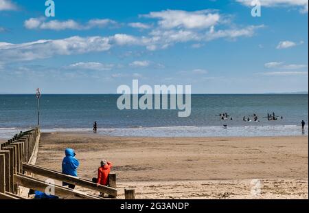 Paddelboarder gehen am Sommertag in Edinburgh, Schottland, Großbritannien, in den Firth of Forth Sea am Portobello Beach Stockfoto