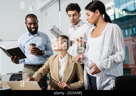 Eine Geschäftsfrau, die auf den Laptop zeigte, lächelte fast und überraschte die Kollegen aus verschiedenen ethnischen Gruppen Stockfoto