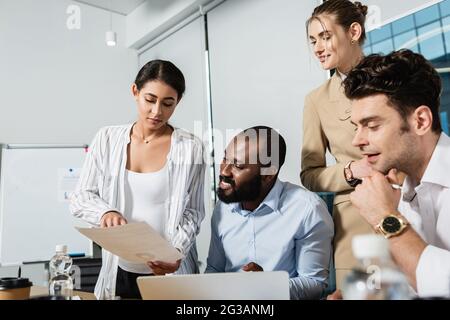 Schwanger afroamerikanische Geschäftsfrau zeigt Dokument lächelnden Kollegen Stockfoto