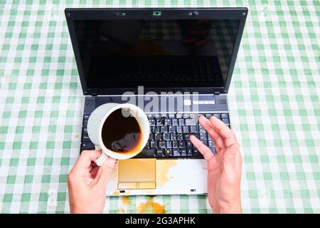 Notizbuch schüttete ungemülich Kaffee aus einer Tasse. Computerunfall. Laptop mit Flüssigkeit zerstört. Kaffee verschüttet auf Laptop-Tastatur. Verschütten von Kaffee Stockfoto