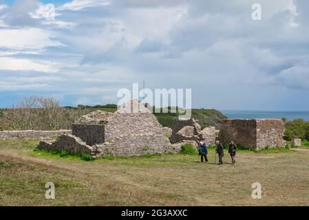 Ältere Menschen gehen, Blick auf drei ältere Freunde, die in den Ruinen des Southern Fort in Berry Head in Torbay, Devon, England, Großbritannien, spazieren gehen Stockfoto