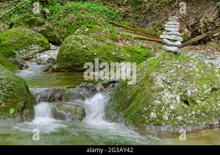 Rock Stack, neben einem wilden Bach. Stapel von gestapelten Felsen, balanciert auf einem großen Felsen in einem Streambed. Felsen, die flach auf einander zu großer Höhe gelegt wurden. Stockfoto