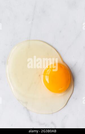 Ein einziges rohes Ei auf einer Marmorplatte Stockfoto