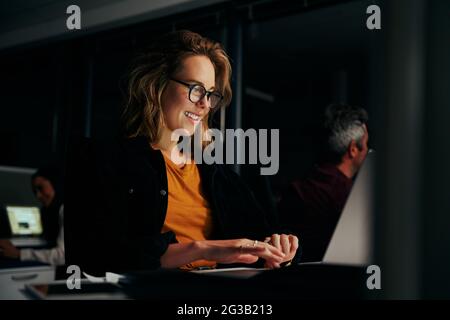 Erfolgreiches junges lächelndes Porträt einer Geschäftsfrau, die im modernen Büro auf dem Laptop tippt Stockfoto