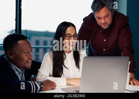 Erfolgreiche junge, vielfältige Gruppe von Geschäftsleuten, die im modernen Büro an einem Laptop arbeiten Stockfoto