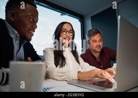 Verschiedene Kollegen, die bei der Arbeit an einem neuen Geschäftsprojekt gemeinsam einen Laptop verwenden Stockfoto