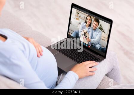 Konzept Der Online-Kommunikation. Nicht erkennbare Schwangere, die zu Hause mit Freunden auf einem Laptop einen Videoanruf abruft, werdende Frauen, die mit jungen Menschen chatten Stockfoto