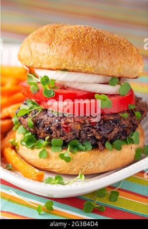 Gesunder gegrillter Burger mit schwarzen Bohnen und Pommes auf gestreiftem Leinen Stockfoto