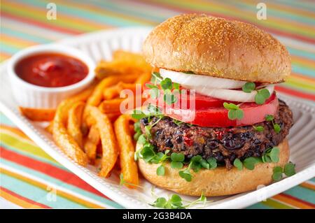 Gesunder gegrillter Burger mit schwarzen Bohnen und Pommes auf gestreiftem Leinen Stockfoto