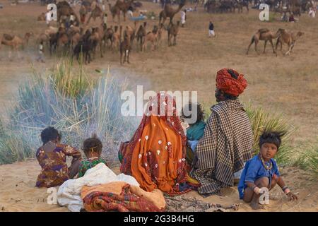 Familiengruppe um ein offenes Feuer nach einer Nacht schlafen im Freien auf der jährlichen Pushkar Messe in Rajasthan Indien. Stockfoto