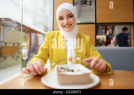 Junge muslimische Frau im Hijab, die im Café zu Mittag gegessen hat Stockfoto
