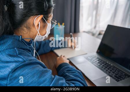 Asiatische Teenager-Mädchen Schulschülerin trägt Kopfhörer Fernunterricht online in der virtuellen Klasse mit Lehrer Tutor auf Laptop durch Videokonferenz anrufen, beobachten Stockfoto