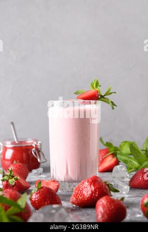 Indische Erdbeere Lassi oder Milchshake auf grauem Hintergrund. Vertikales Format. Traditionelles ayurvedisches gesundes Getränk mit Erdbeeren Joghurt, Früchten und Stockfoto