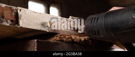 Alte Holztüren mit einem Spachtel und einer Heißluftpistole abfärben, alte Holzflächen-Panorama wiederherstellen. Stockfoto