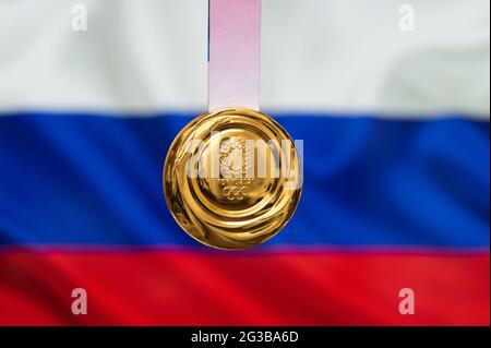 25. April 2021 Tokio, Japan. Goldmedaille der XXXII. Olympischen Sommerspiele 2020 in Tokio auf dem Hintergrund der russischen Flagge. Stockfoto