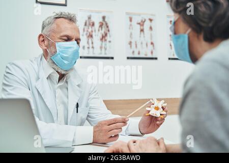 Der Arzt erklärt die Grundlagen der Wirbelsäulenanatomie während der Patientenkonsultation Stockfoto