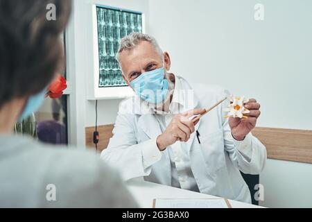 Ein erfahrener Vertebrologe erklärt einem Patienten die Grundlagen der Wirbelsäulenanatomie Stockfoto