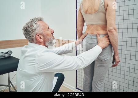 Physiatrikerin, die eine Lendenwirbelsäule einer weiblichen Patientin untersucht Stockfoto