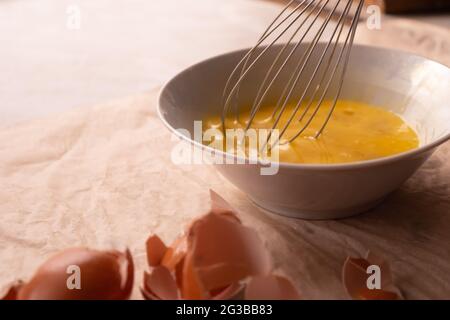 Eier in einem Teller mit einem Schneebesen in der Nähe schlagen. Stockfoto