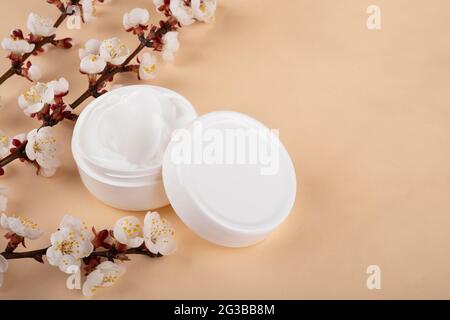 Frühlingsblume und Creme auf beigem Hintergrund. Hautpflege. Stockfoto