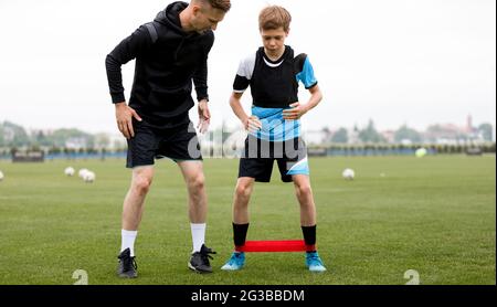 Teenager-Junge mit Fußball-Coach auf Stretching-Sitzung. Training Für Junge Fußballspieler Mit Stretching-Bändern. Workout-Stretching-Bänder Stockfoto