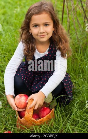 Süß Lächelnd Russische Sechs Jahre Mädchen Halten In Ihrer Hand Frisch Reifen Roten Apfel Im Sommergarten Im Freien. Frische Äpfel Ernten. Stockfoto