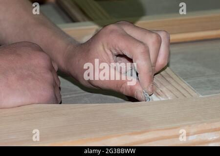 Schleifen von Türen mit Schleifpapier, Türrestaurierung. Stockfoto