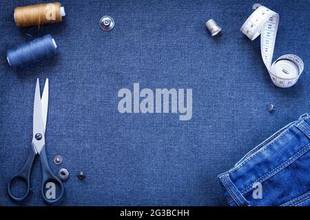 Handarbeit: Schere, Knopf, Faden, Handstück, Zentimeter Klebeband Und Jeans Auf Dem Hintergrund Aus Dunkelblau Grauer Jeans-Stoffansicht. Stockfoto