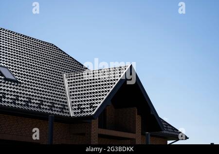 Braunes Wellblech-Profildach auf einem modernen Haus mit Dachfenstern installiert. Das Dach aus Wellblech. Dach des Metallprofils wellig Stockfoto