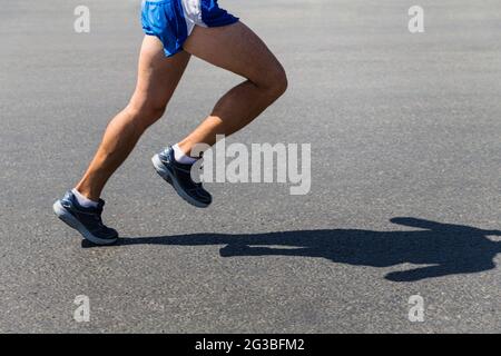 Beine männlicher Läufer-Athlet läuft auf grauem Asphalt Stockfoto