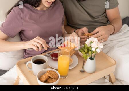 Junge Frau verteilt Marmelade auf Brotscheibe oder Toast Stockfoto