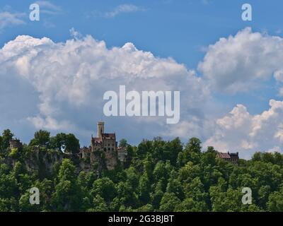 Atemberaubende Aussicht auf das berühmte Schloss Lichtenstein auf einem Felsen am Rande ('Albtrauf') der Schwäbischen Alb, Baden-Württemberg, Deutschland mit grünem Wald. Stockfoto