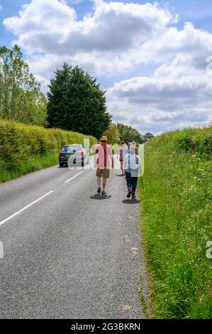 Eine Gruppe von Wanderern, die entlang der South Road gehen, einer asphaltierten Einkutschenstraße zwischen Plumpton Green und South Chailey, East Sussex, England. Stockfoto