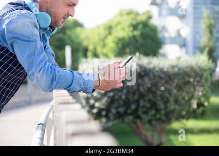 Attraktiver Mann mit Gay-Flagge Armband mit einem Smartphone Stockfoto