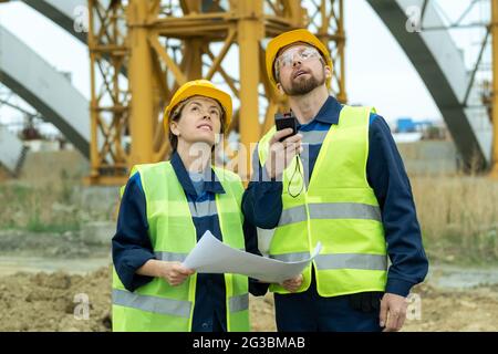 Zwei junge Bauherren blicken während der Bauarbeiten nach oben Stockfoto