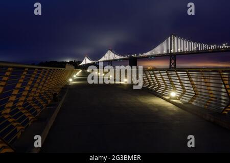 Die Bay Bridge mit Foggy Blue Skies eingerahmt von Pier 14 Railings. San Francisco, Kalifornien, USA. Stockfoto