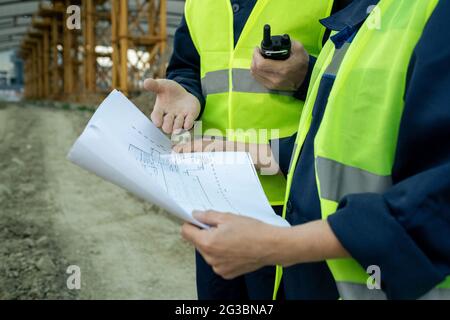 Hände eines männlichen Baumeisters, der einer Kollegin beim Arbeitstreffen die Skizze erklärt Stockfoto
