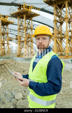 Serious Builder in Uniform und Hardhat mit Tablet und Blick auf Sie Stockfoto
