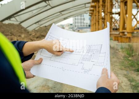 Hand einer Ingenieurin, die während der Diskussion auf die Skizze der unfertigen Konstruktion zeigt Stockfoto