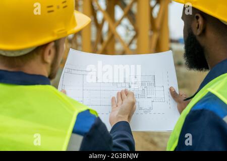 Zwei interkulturelle männliche Bauherren diskutieren Skizze des Neubaus Stockfoto