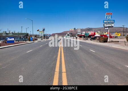 Blick geradeaus auf die zentralen gelben Linien eines Abschnitts der Route 66, wo sie durch eine kleine Stadt mit Motel- und anderen Schildern nach Arizona, USA, führt Stockfoto